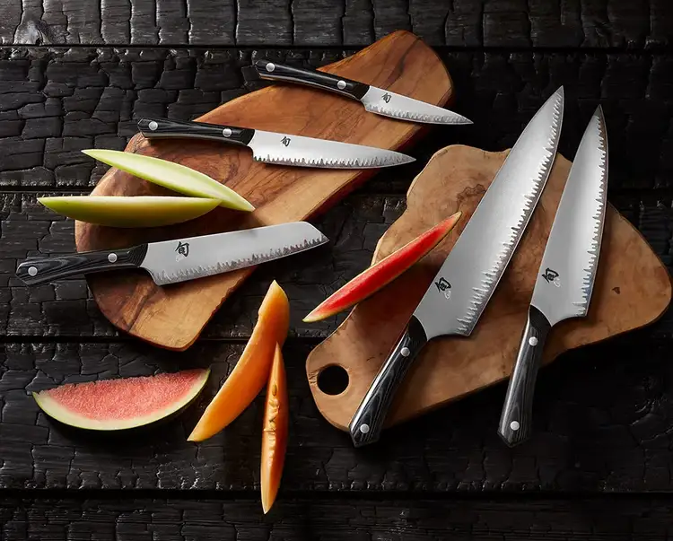 A group of Narukami knives lie on a serving board next to thinly sliced wedges of melon.