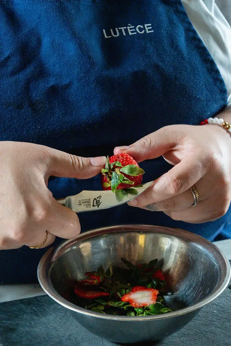 Close up of Chef Ana Sofia Pino cutting strawberries with a Shun Classic Bird's Beak knife while wearing a Lutèce apron.