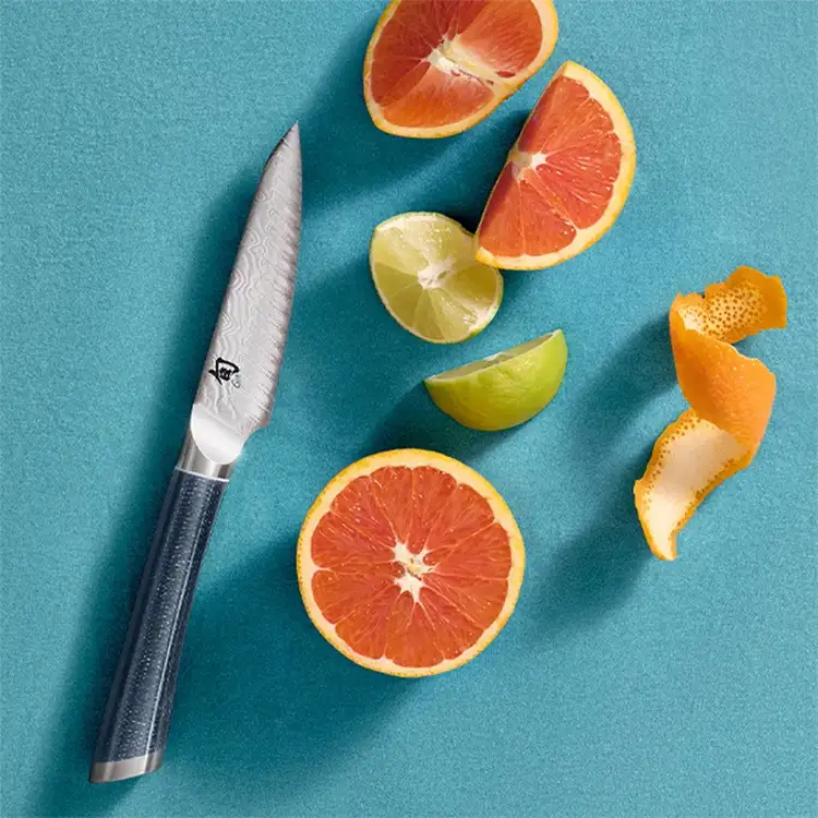 Shun Shiranami 4-inch paring knife with citrus slices on blue background