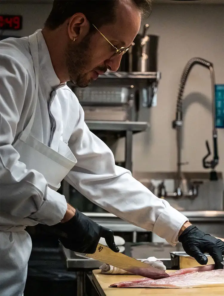 Chef Jason Chavenson cuts through a fish filet with the Dual Core 10.5" Yanagiba.