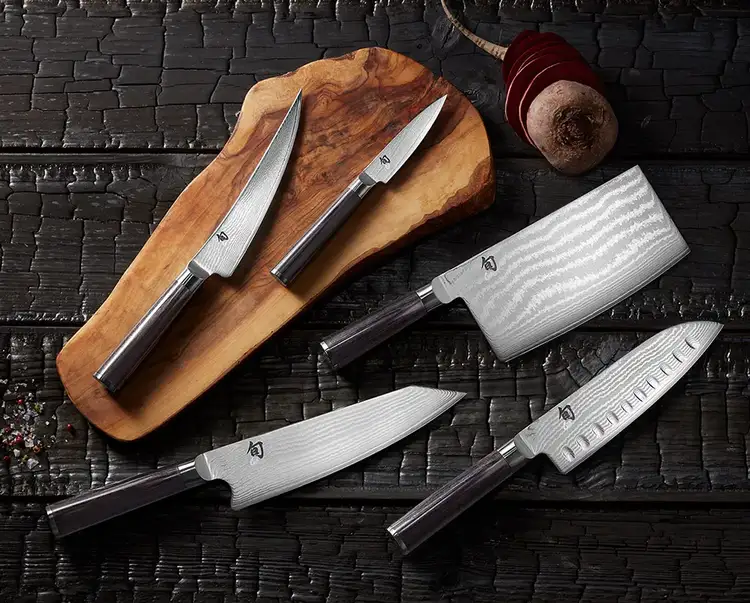 A grouping of five Classic knives lie on a serving board next to a sliced beet.