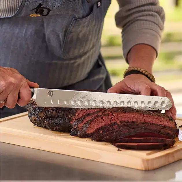 A pitmaster slices brisket with a Classic Brisket Knife.
