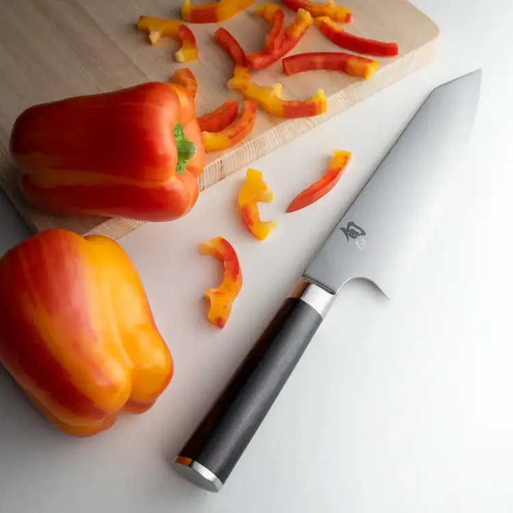 Shun Classic Kiritsuke knife beside sliced bell peppers on a cutting board. Click to shop.