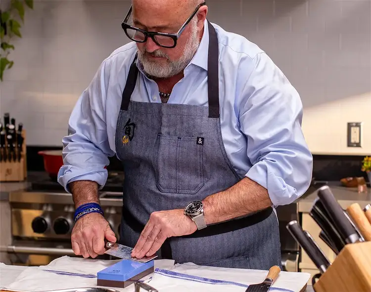 Chef Andrew Zimmern sharpens a nakiri on a whetstone.