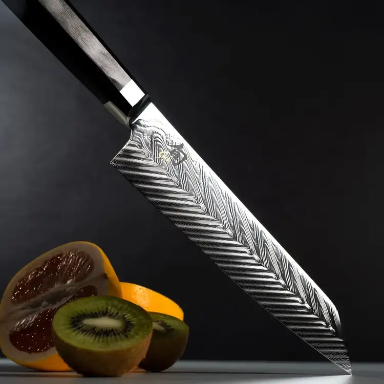Close-up of Shun Dual Core Kiritsuke knife blade with herringbone Damascus pattern and sliced kiwi and citrus. Click to shop.