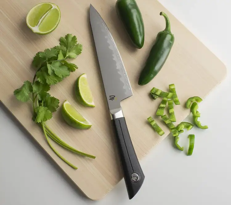 A Classic 6" Chef's Knife sits next to slices of pineapple on a hinoki cutting board.
