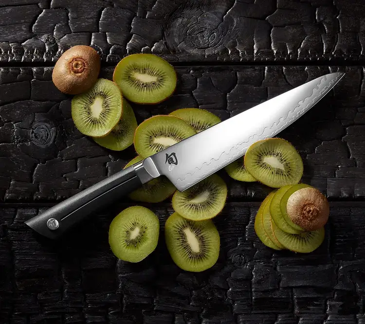 A Sora 8" Chef's Knife rests on slices of green kiwi.