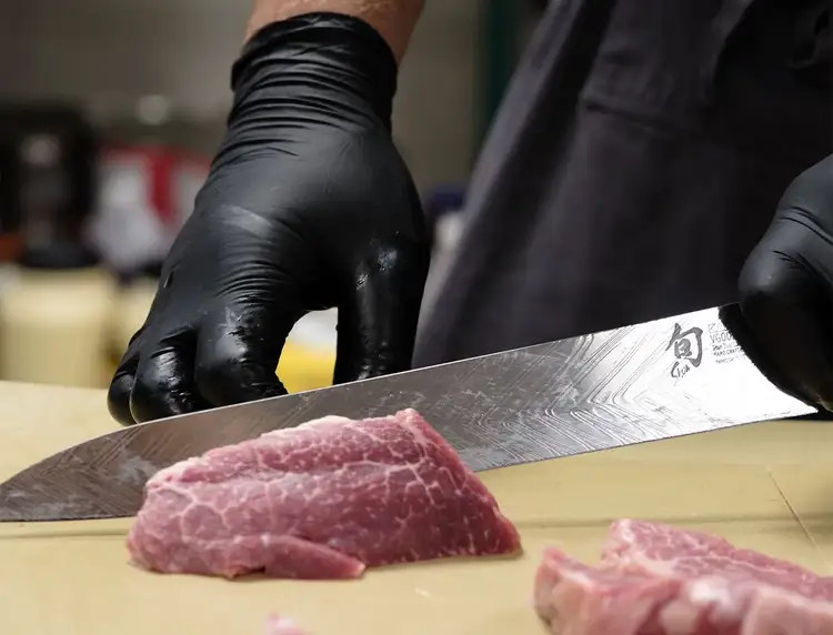 Chef Kyle Morse slices through a cut of meat with a 10.5" Shun Dual Core Yanagiba knife